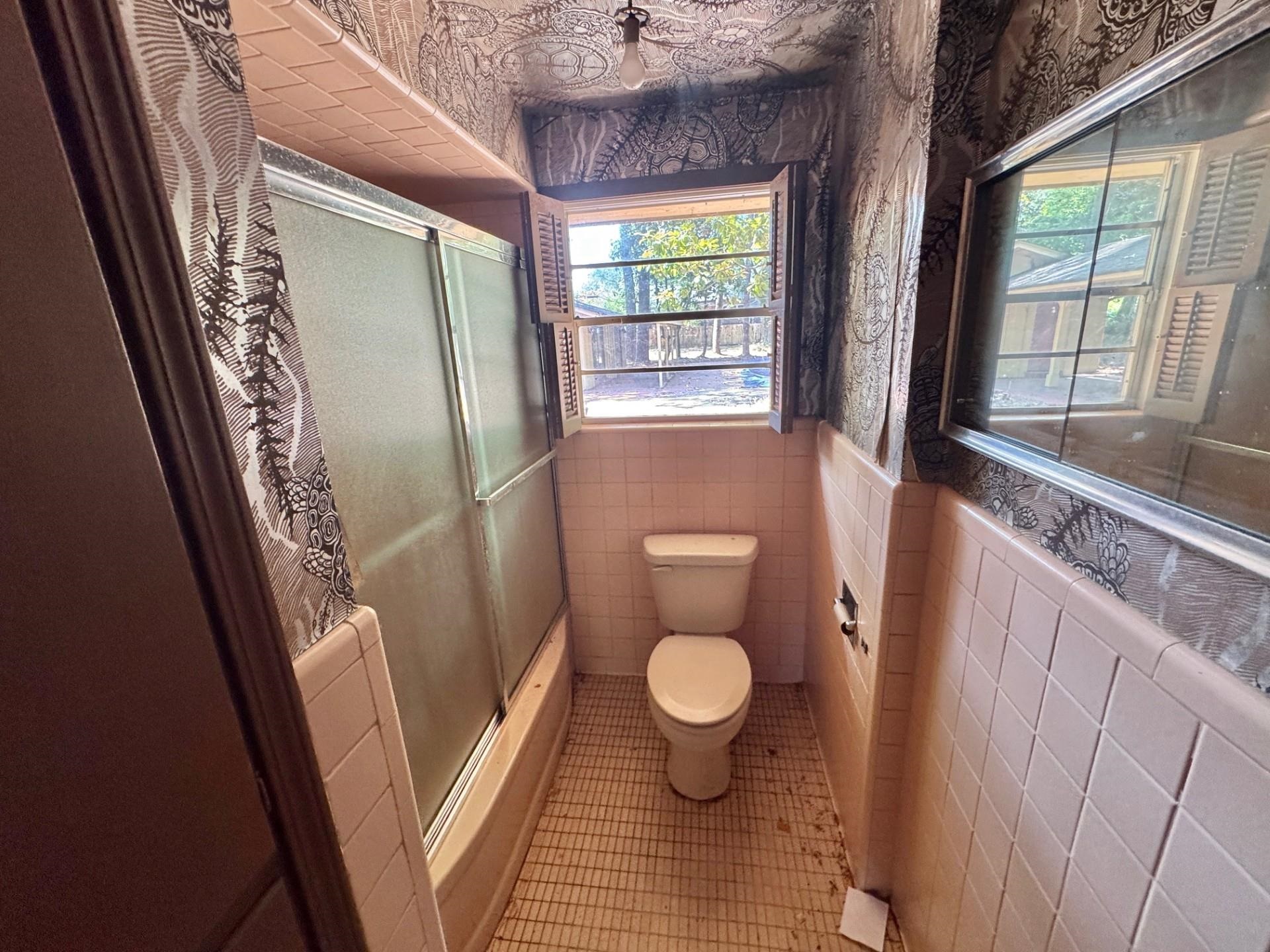 5429 Normandy Road Memphis, TN 38120 - Photo 18 of 25 Full bath featuring toilet, tile walls, wainscoting, tile patterned flooring, and shower / bath combination with glass door