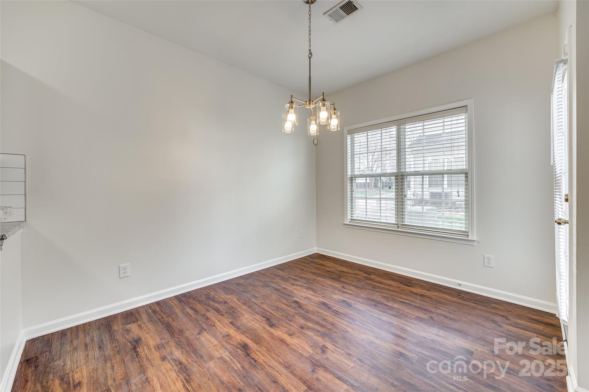 2035 Lennox Square Road Charlotte, NC 28210 - Photo 8 of 29 an empty room with wooden floor chandelier and windows
