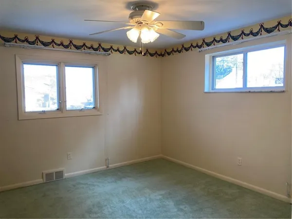 en empty room with a chandelier fan and window