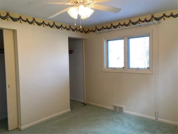 an empty room with a chandelier fan and a window