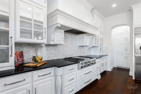 a kitchen with stainless steel appliances granite countertop white cabinets and a stove