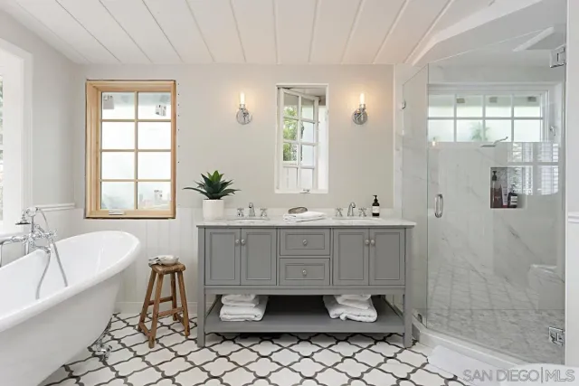 a spacious bathroom with a double vanity sink a mirror a bathtub and next to a window