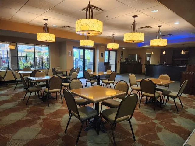 a view of a dining room with furniture a chandelier and large windows