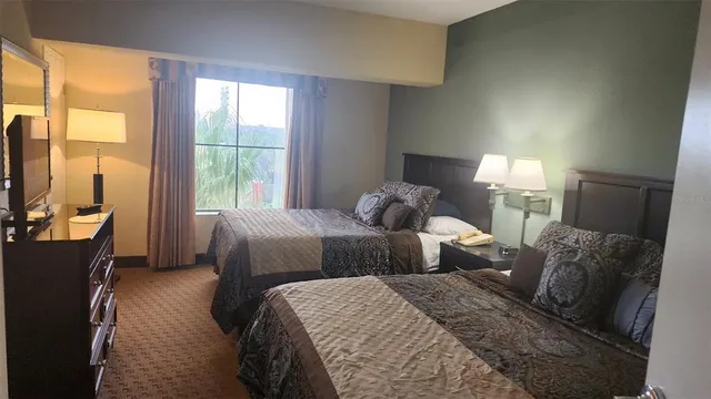 a bedroom with two beds and large windows