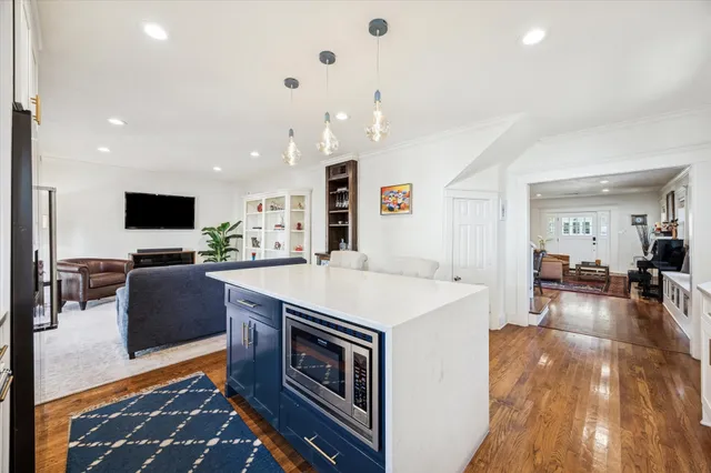 a dining hall with stainless steel appliances kitchen island granite countertop a dining table chairs and a refrigerator