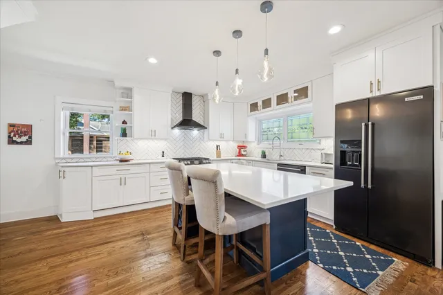 a kitchen with stainless steel appliances granite countertop a table chairs refrigerator and sink