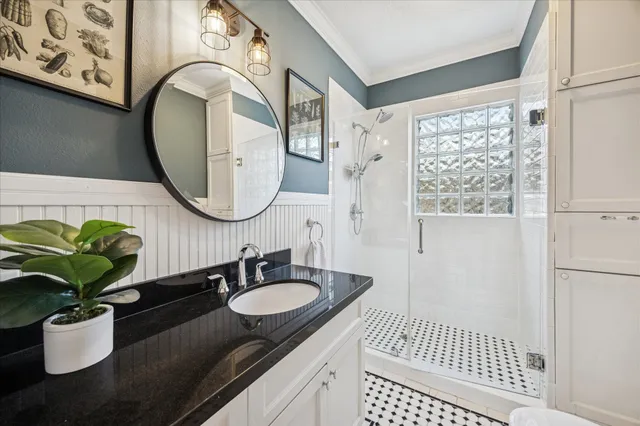 a bathroom with a granite countertop sink a mirror and shower