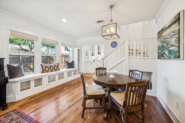 a dining room with wooden floor a chandelier a wooden table and chairs