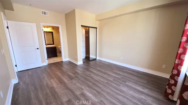 a view of an empty room with wooden floor and closet