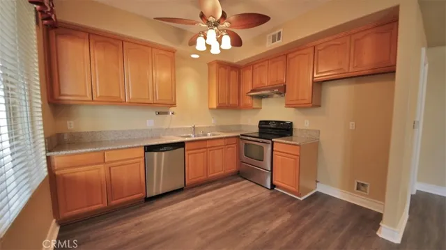 a kitchen with granite countertop wooden floors white cabinets and stainless steel appliances