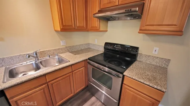 a kitchen with granite countertop a sink stove and cabinets