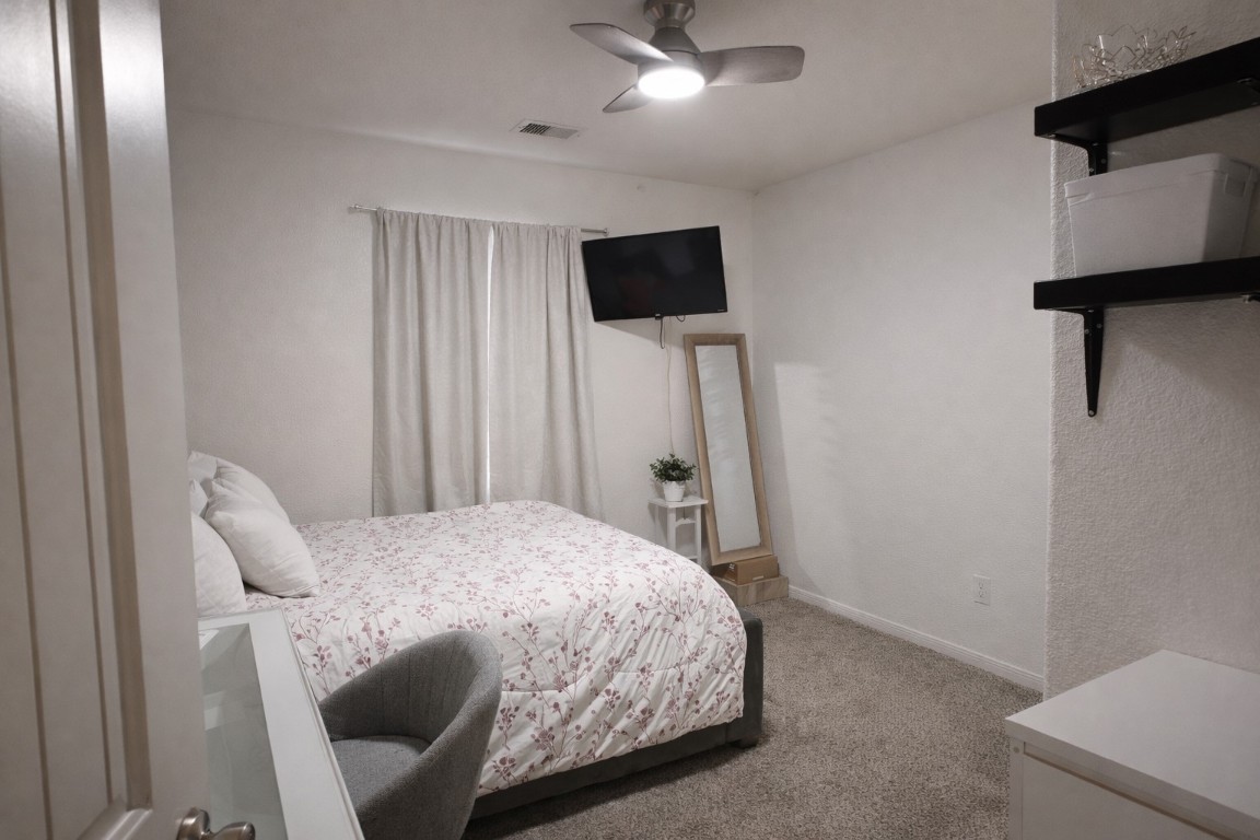 250 7th Street Hempstead, TX 77445 - Photo 18 of 26 a bedroom with a bed a flat screen tv and a ceiling fan