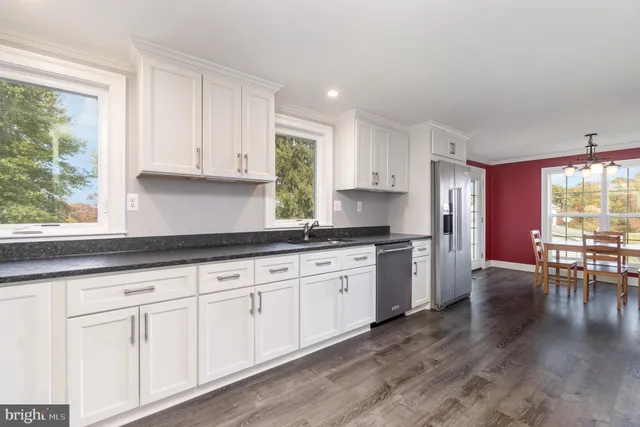 a kitchen with granite countertop white cabinets a sink a window and stainless steel appliances