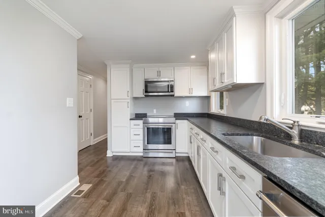 a kitchen with granite countertop white cabinets and white appliances