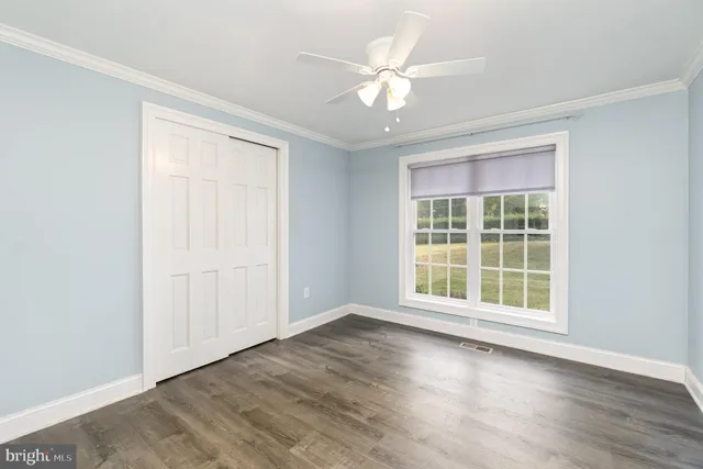 an empty room with wooden floor fan and windows