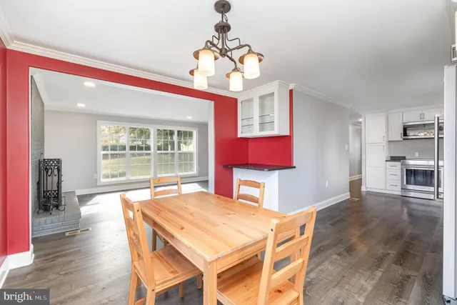 a dining room with wooden floor a chandelier a wooden table and chairs