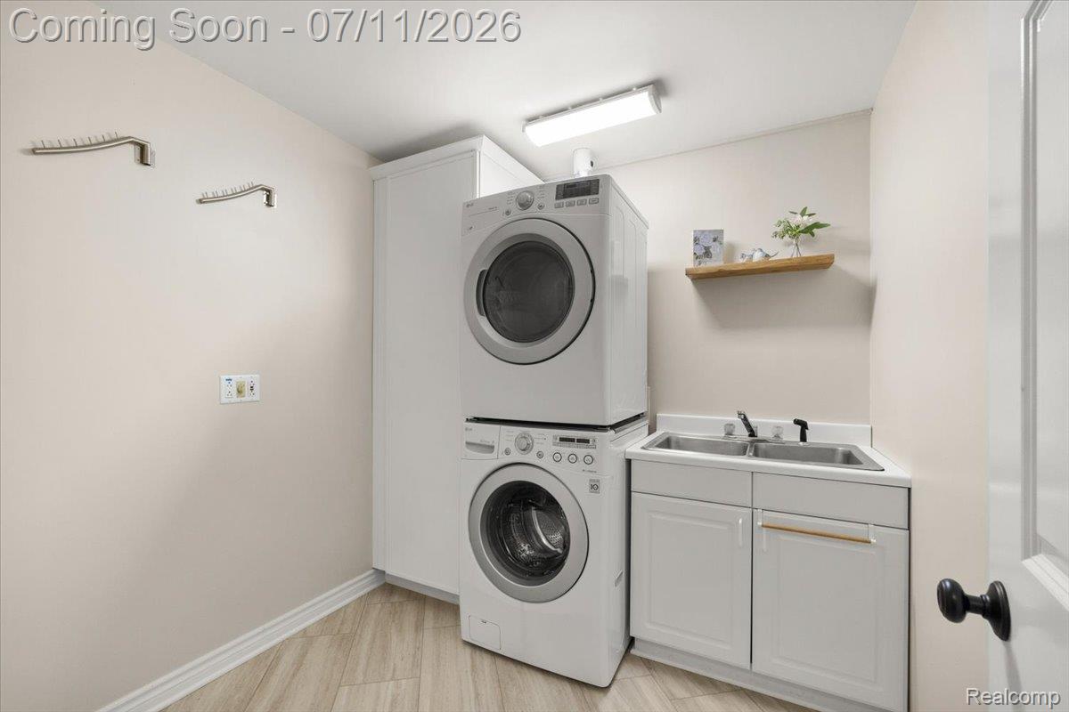 4219 Gardner Road Metamora, MI 48455 - Photo 43 of 87 Dedicated laundry area featuring wood-finish flooring, a utility sink with a dual basin, lower cabinetry, and a stacked appliance configuration