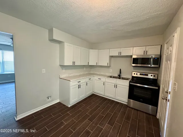 a kitchen with granite countertop a refrigerator and a stove top oven
