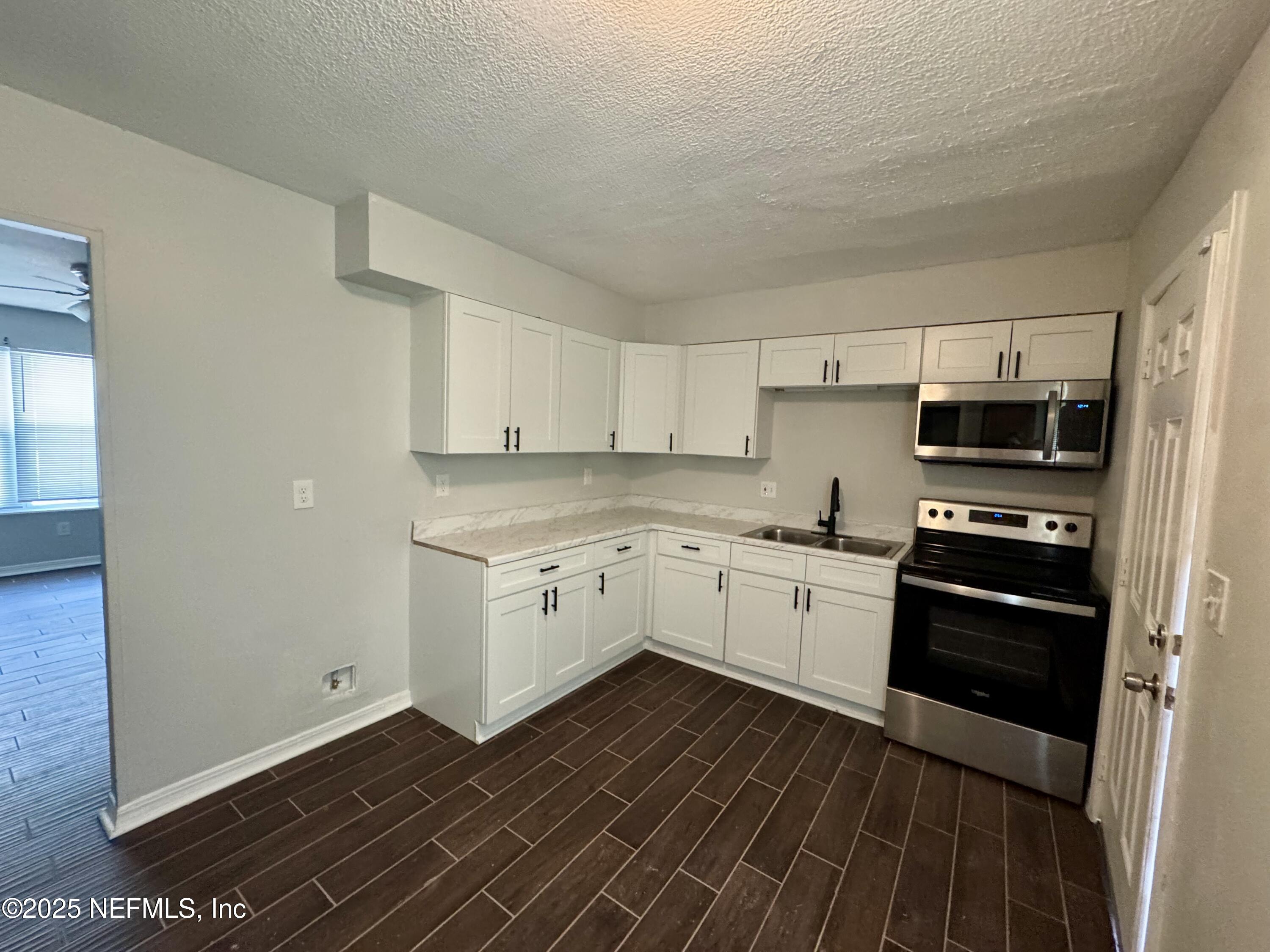707 Rainer Road, Unit 3 Baldwin, FL 32234 - Photo 4 of 11 a kitchen with granite countertop a refrigerator and a stove top oven