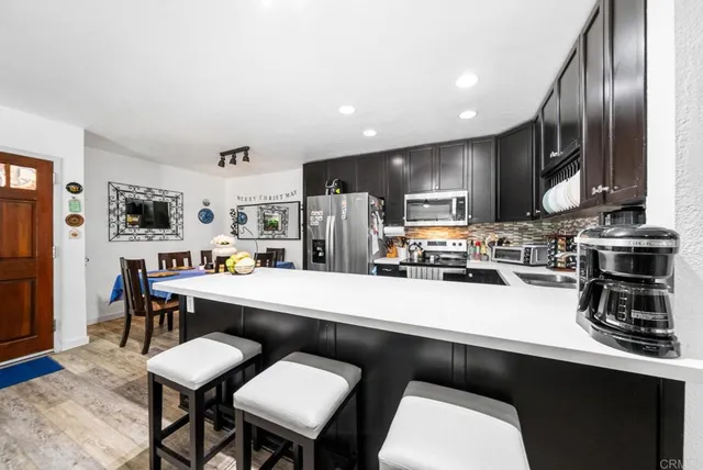 a kitchen with stainless steel appliances a sink a stove a refrigerator cabinets and a dining table