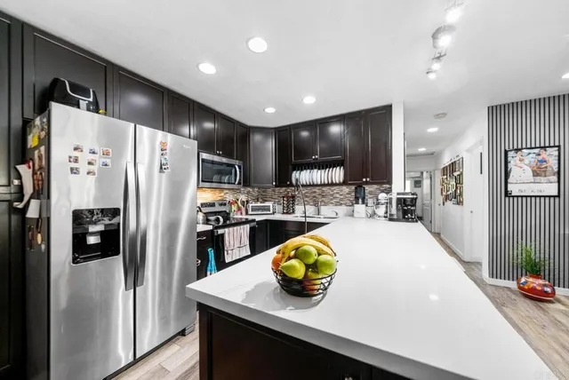 a kitchen with a sink a refrigerator and chairs