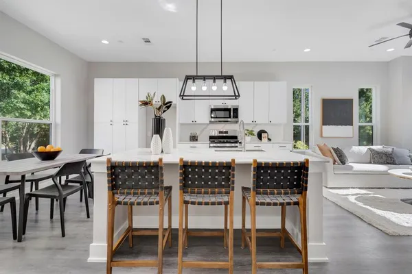a kitchen with stainless steel appliances granite countertop a stove top oven a sink a dining table and chairs with wooden floor