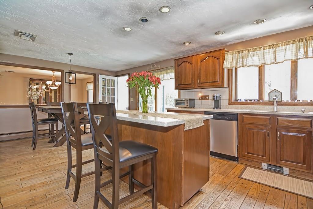 50 Cedarcrest Road Canton, MA 02021 - Photo 10 of 42 a kitchen with stainless steel appliances granite countertop a stove a sink dishwasher a dining table and chairs with wooden floor