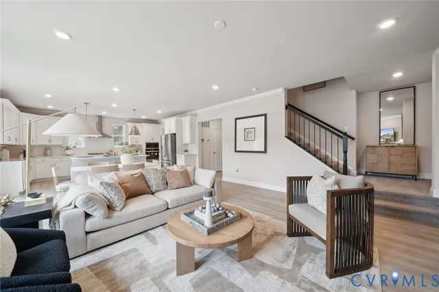 a living room with furniture kitchen view and a wooden floor