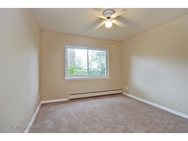 2315 South Goebbert Road, Unit D106 Arlington Heights, IL 60005 - Photo 8 of 11 an empty room with windows and ceiling fan