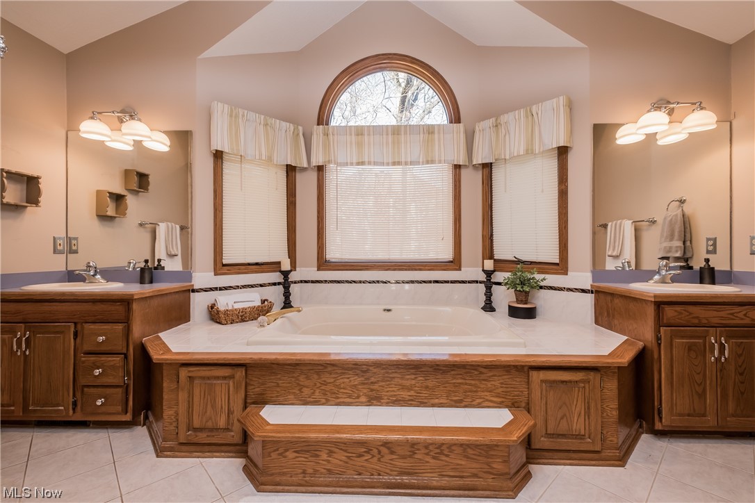 6216 Rockside Circle Northwest Canton, OH 44718 - Photo 22 of 33 Bathroom with vaulted ceiling, double sink vanity, and a jetted bath tub