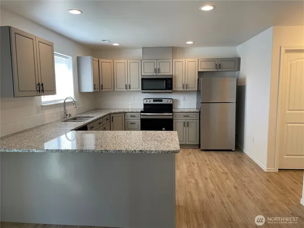 a kitchen with granite countertop a refrigerator sink and microwave