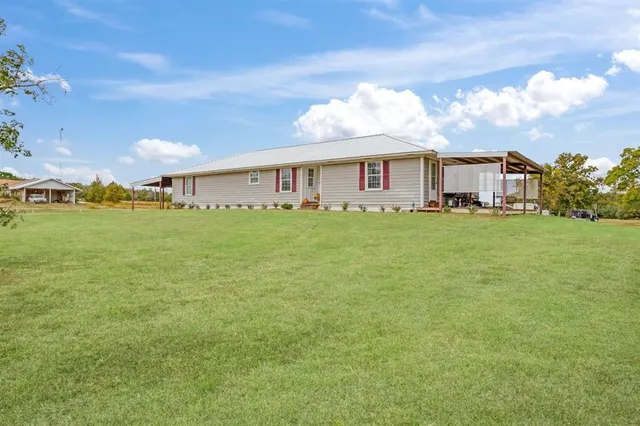 a view of a house with a big yard and large trees