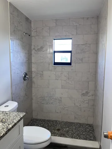a bathroom with a granite countertop toilet a sink and shower