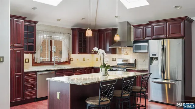 a kitchen with stainless steel appliances granite countertop a refrigerator a stove top oven a sink and cabinets