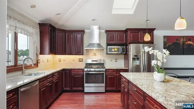 a kitchen with stainless steel appliances granite countertop a sink a stove and a wooden cabinets