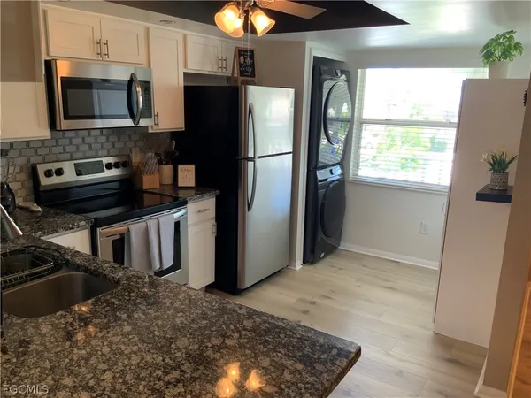 a kitchen with stainless steel appliances granite countertop a refrigerator a stove a sink and a window