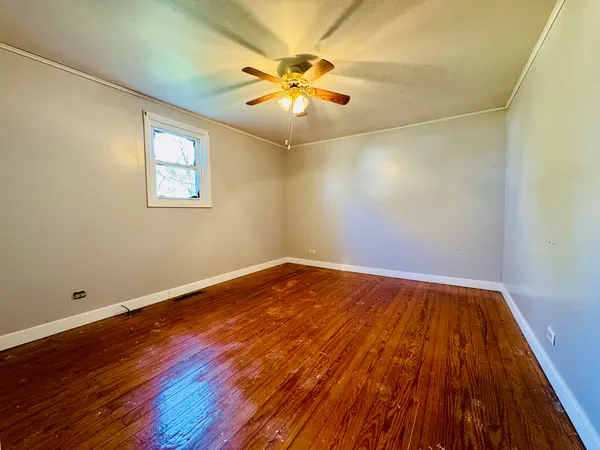 an empty room with wooden floor and fan