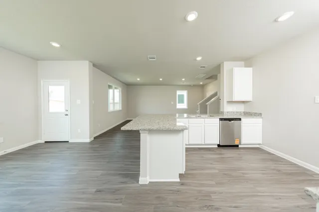 an open kitchen with white cabinets and wooden floor