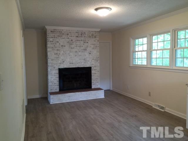 536 Gay Road Zebulon, NC 27597 - Photo 4 of 4 an empty room with wooden floor fireplace and windows