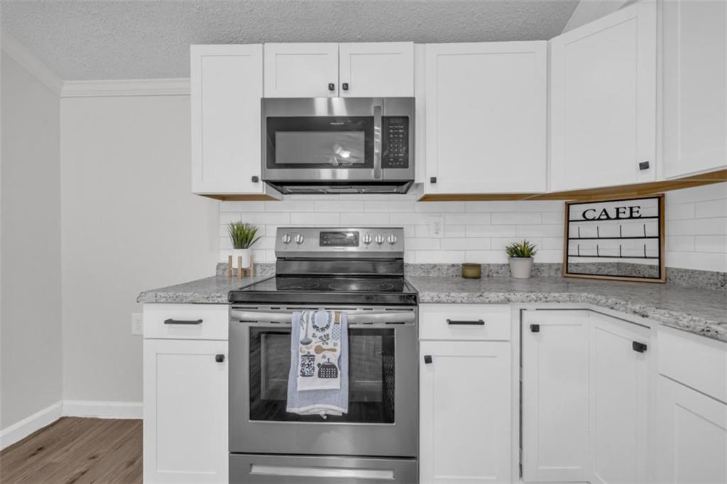 9597 Highway 334 Nicholson, GA 30565 - Photo 16 of 41 a kitchen with stainless steel appliances granite countertop a stove a microwave and wooden cabinets
