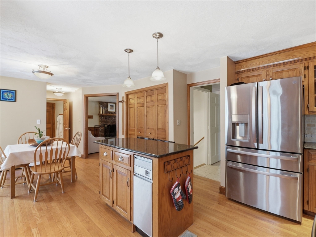 10 Berkeley Lane Andover, MA 01810 - Photo 7 of 42 a kitchen with stainless steel appliances granite countertop a refrigerator a stove a sink dishwasher and a dining table with wooden floor