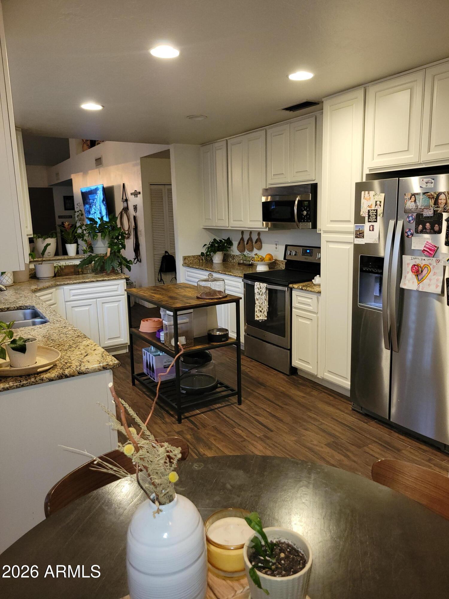 6736 South Wilson Street Tempe, AZ 85283 - Photo 8 of 13 a kitchen with stainless steel appliances granite countertop a refrigerator a stove a sink dishwasher and a dining table with white countertops