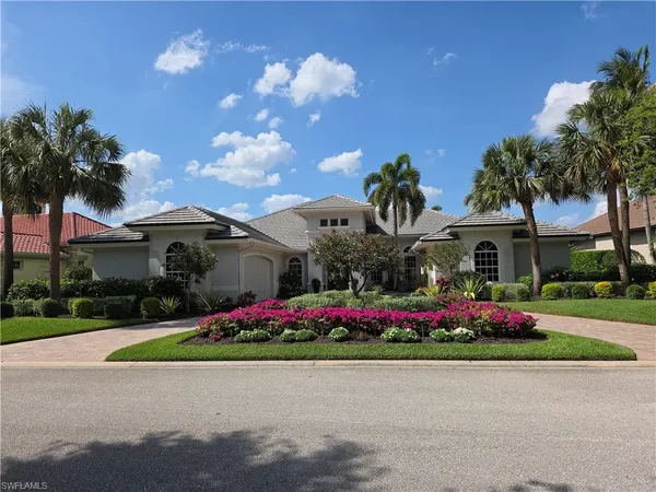 a front view of a house with a yard and fountain in middle