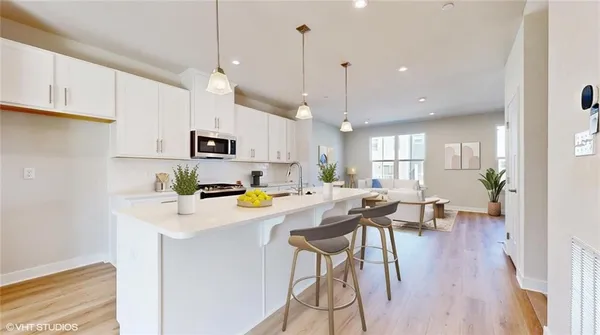 a kitchen with stainless steel appliances a white stove top oven a sink dishwasher and a refrigerator with wooden floor