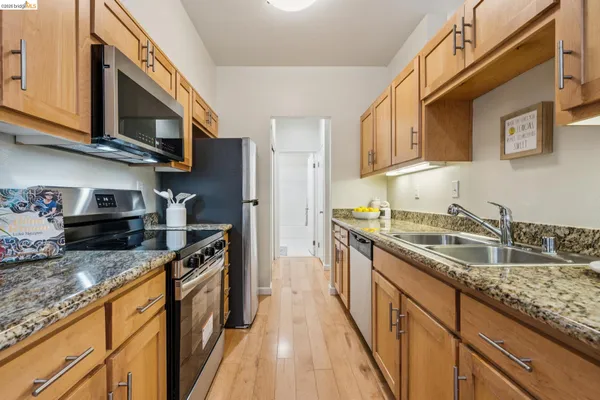a kitchen with granite countertop stainless steel appliances a sink a stove top oven a counter space and cabinets