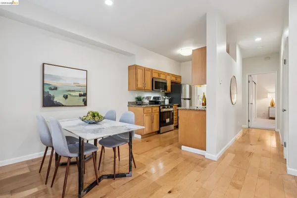 a kitchen with stainless steel appliances kitchen island granite countertop a refrigerator a stove a microwave oven a dining table and chairs with wooden floor