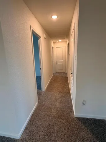 an empty room with wooden floor and a hallway