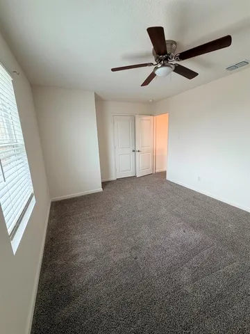 an empty room with windows and fan