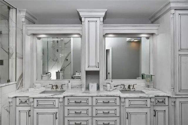 a bathroom with a granite countertop double vanity sink mirror and shower