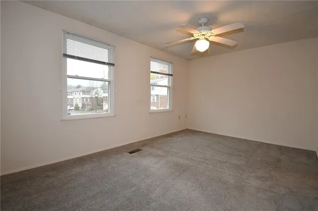 an empty room with windows and fan